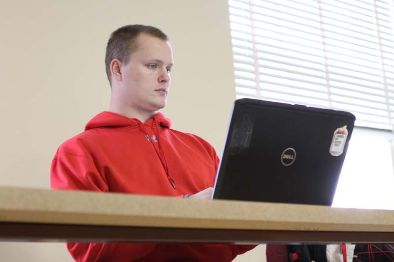 a man in a red sweatshirt using a laptop