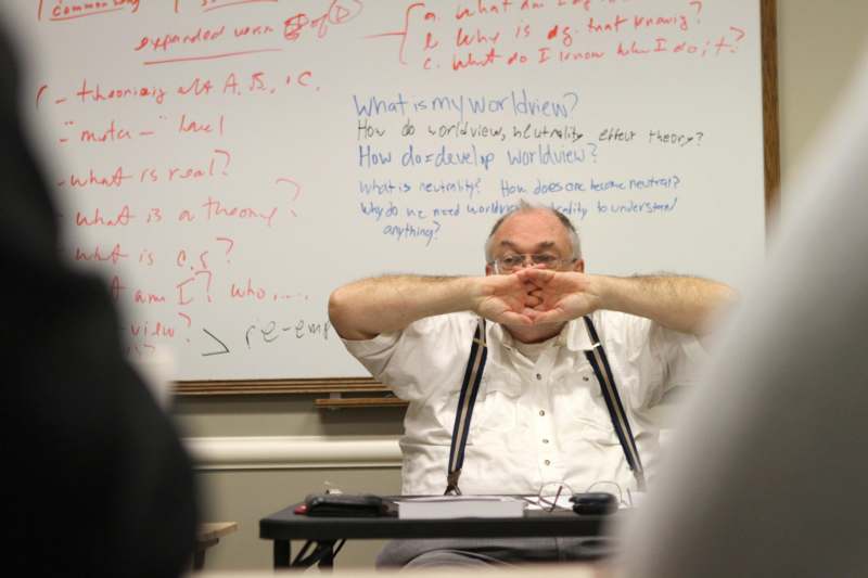 a man sitting in front of a whiteboard with his hands on his face