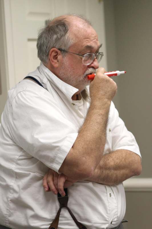 a man in glasses holding a marker in his mouth