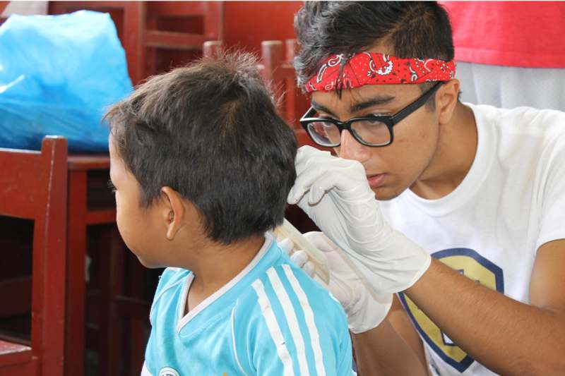 a man wearing glasses and gloves examining a child