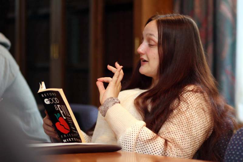 a woman sitting at a table reading a book