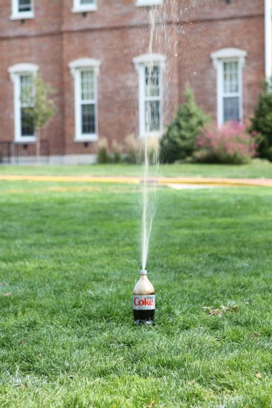 a soda bottle spraying water out of the grass