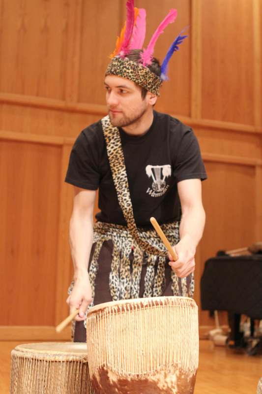 a man wearing a headband and a hat playing a drum