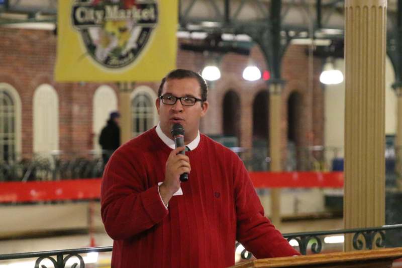 a man in a red sweater speaking into a microphone