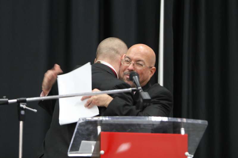 a man hugging another man at a podium