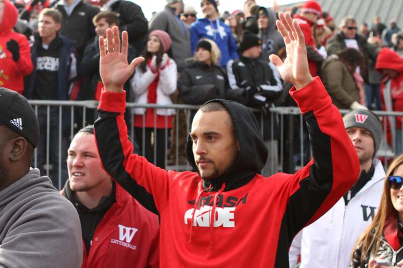a man in a red hoodie raising his hands up
