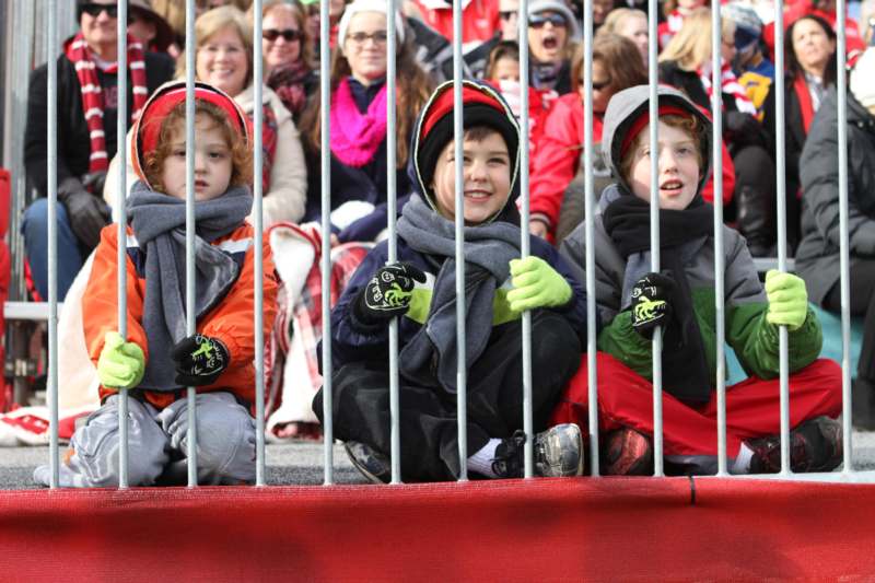 a group of children sitting behind a fence