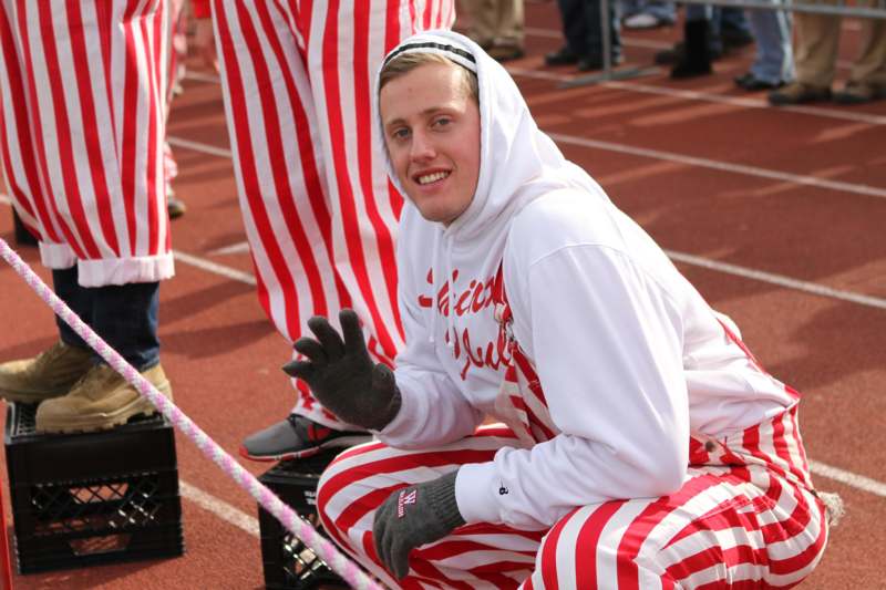 a man in a white hoodie and red striped pants sitting on a track