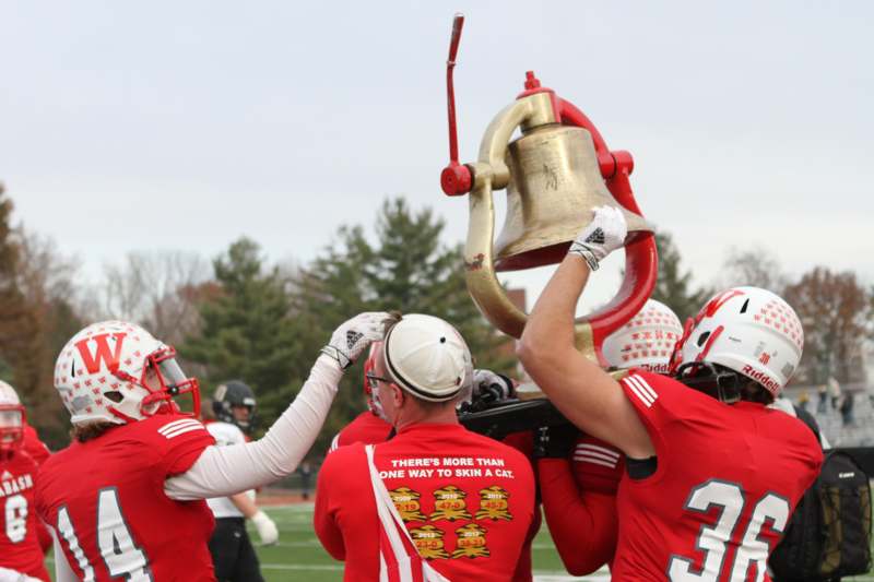 a group of football players holding a bell