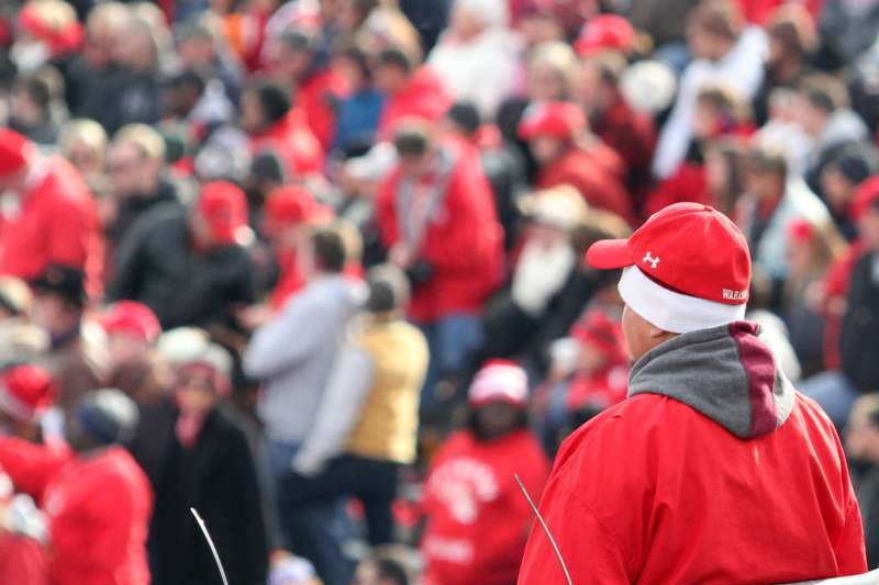 a man in red jacket and hat with a crowd of people in the background