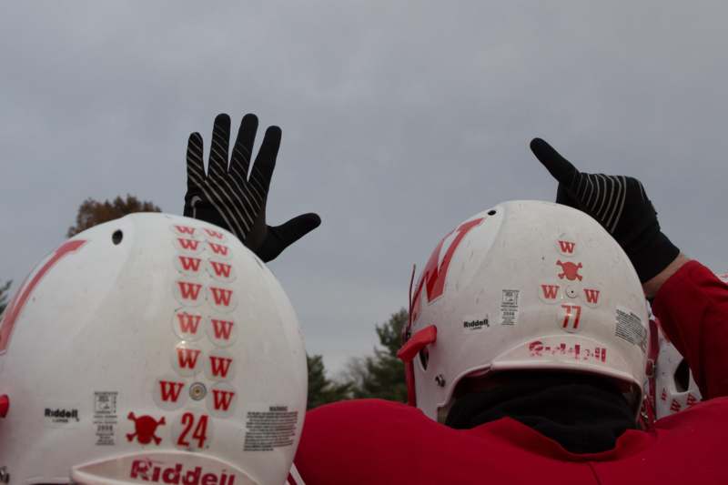 two people wearing helmets with their hands up
