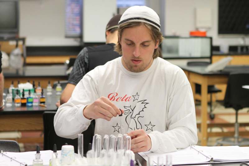 a man in a white hat holding a test tube
