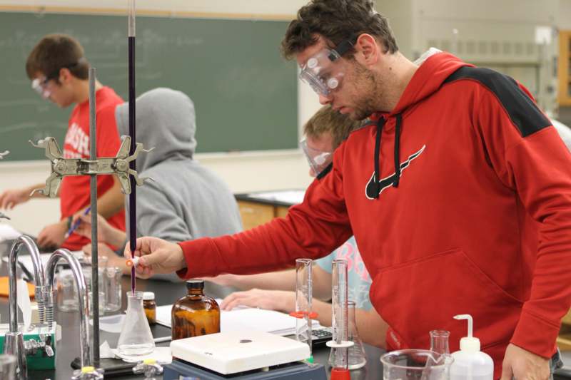 a man wearing goggles and holding a tube with liquid in it
