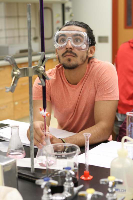 a man wearing goggles and looking at a test tube