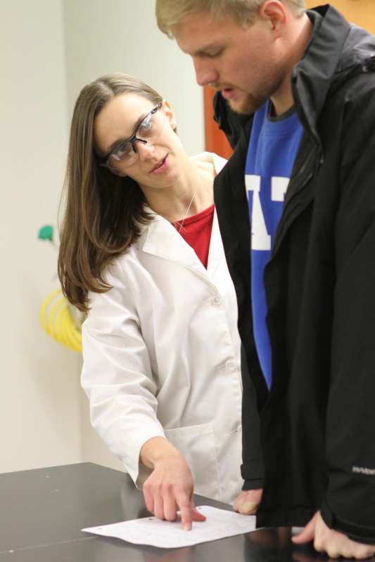 a woman in a white coat and glasses looking at a man