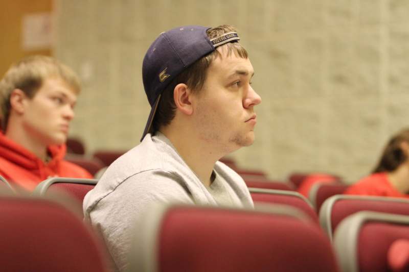 a man in a hat sitting in a lecture hall
