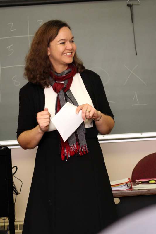 a woman in a black dress and scarf holding a piece of paper