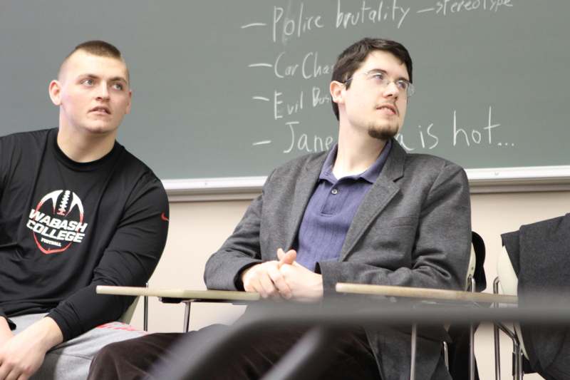 two men sitting at desks in a classroom