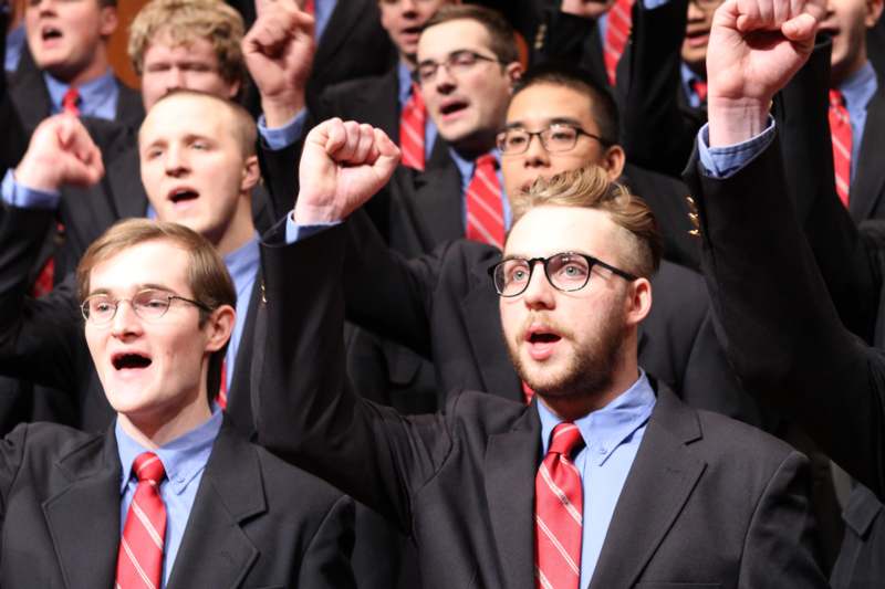 a group of men in suits with their hands up