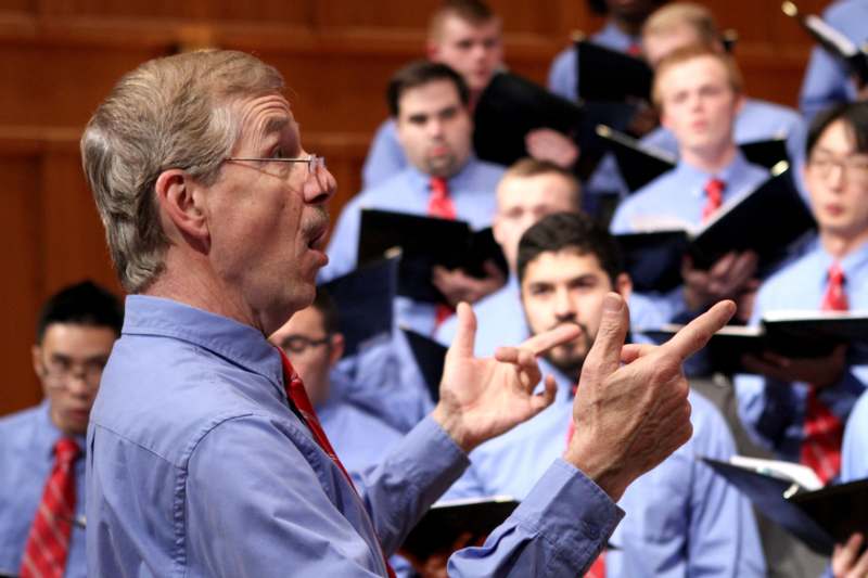a man in a blue shirt speaking to a group of men