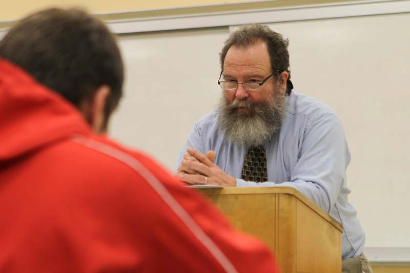 a man sitting at a podium with a beard