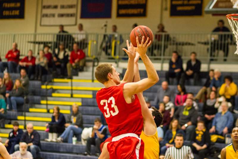 a basketball player in red and yellow uniform making a jump shot