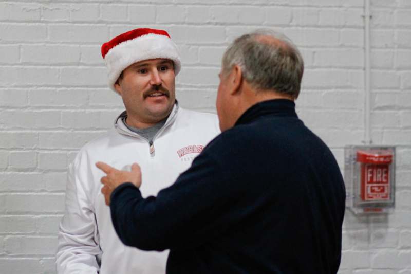 a man wearing a santa hat and pointing at another man