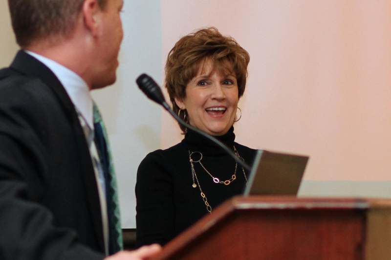 a woman smiling at a man at a podium