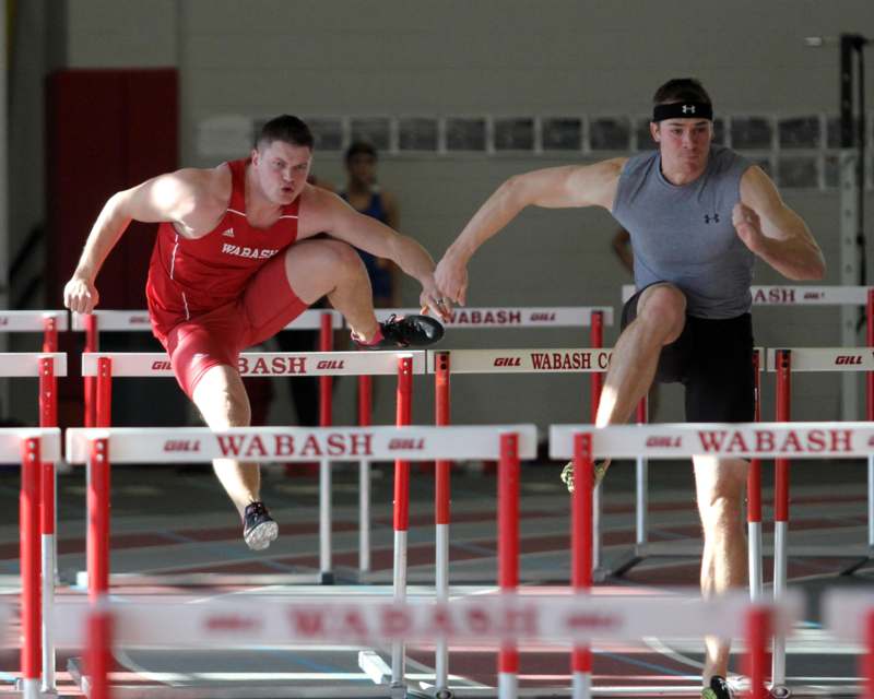 two men jumping over hurdles