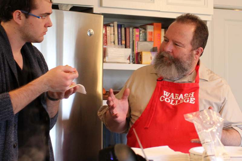 a man in an apron talking to a man in a kitchen