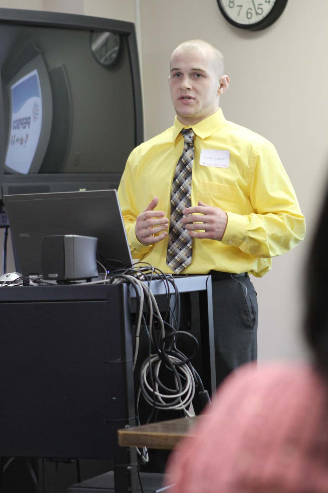 a man in a yellow shirt and tie standing next to a computer