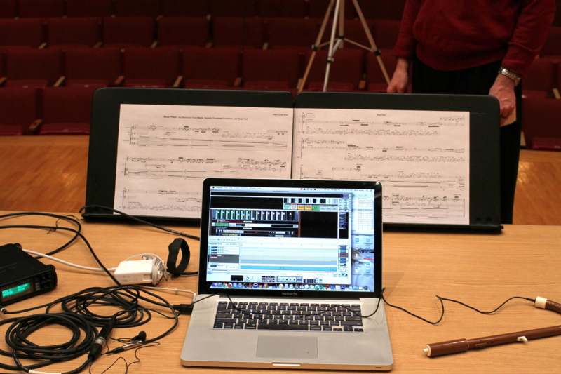 a laptop on a table with music sheets and a pen and headphones