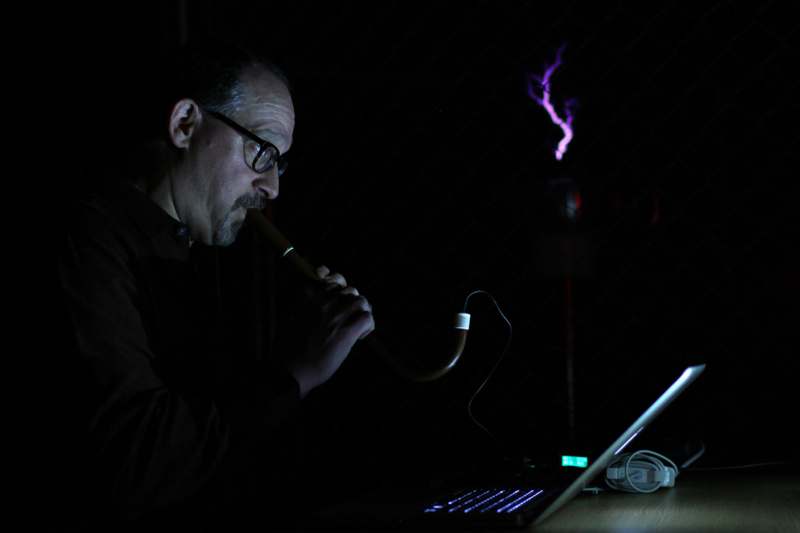 a man smoking a pipe in front of a laptop