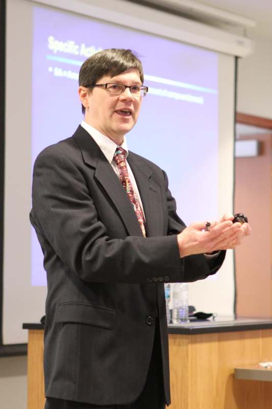 a man in a suit and tie giving a presentation