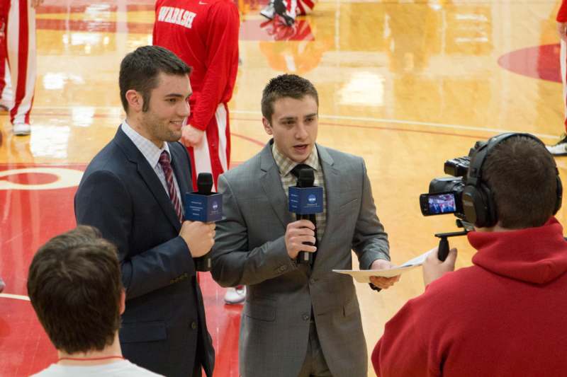 a man in suit holding microphones and a man in red shirt