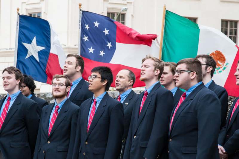 a group of men in suits and ties standing in front of a building