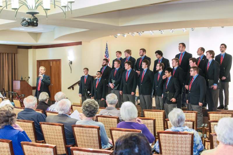 a group of men in suits standing in front of an audience