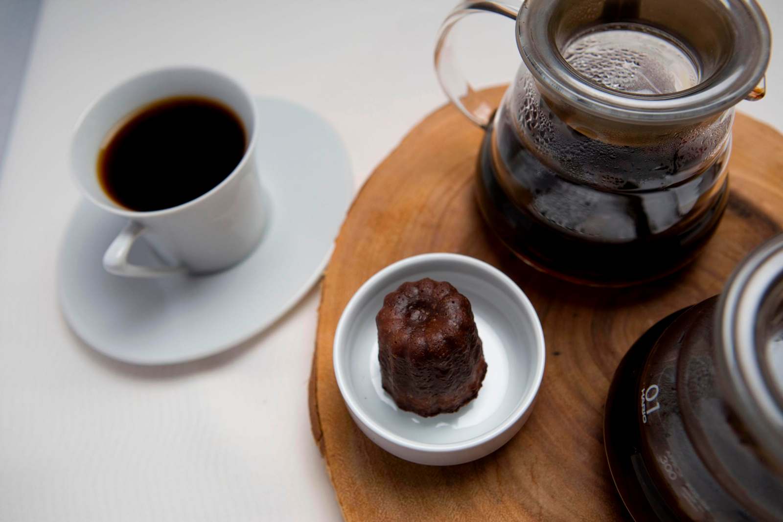 a small chocolate cake in a small white bowl next to a cup of coffee
