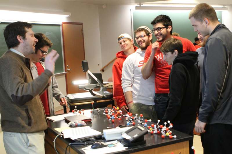 a group of people standing around a table with a model of molecules