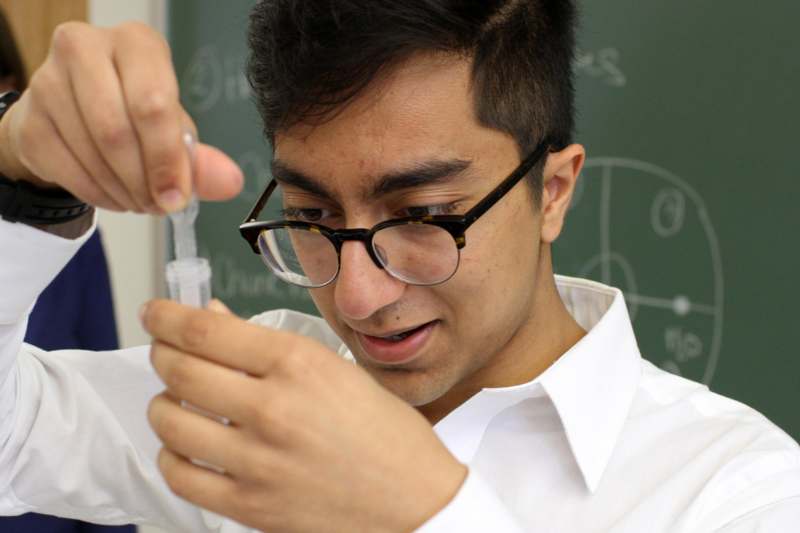 a man wearing glasses and holding a syringe
