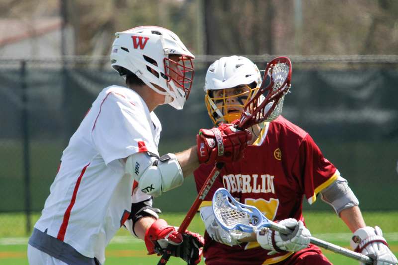 two men wearing helmets and holding lacrosse sticks