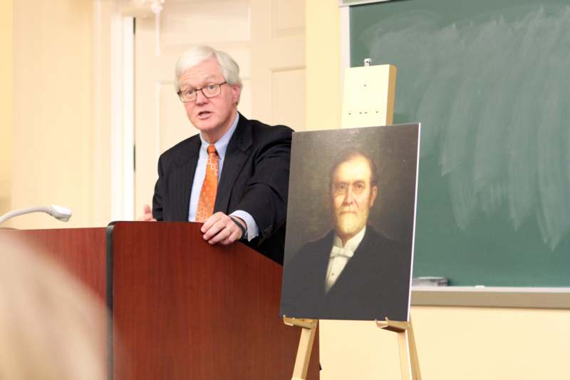 a man standing at a podium with a painting on it