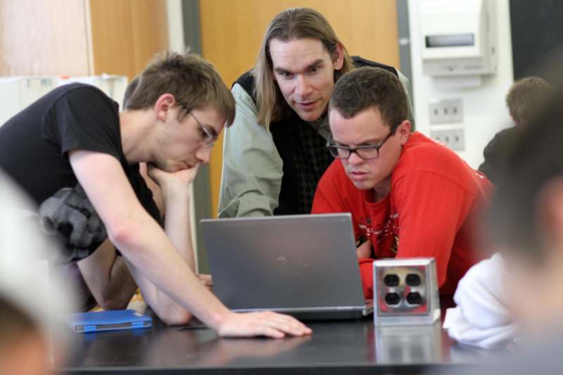 a group of men looking at a laptop