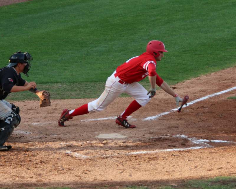a baseball player in red and white uniform running to bat