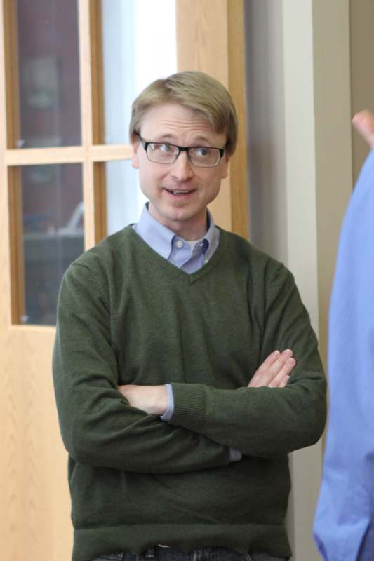 a man wearing glasses and a green sweater