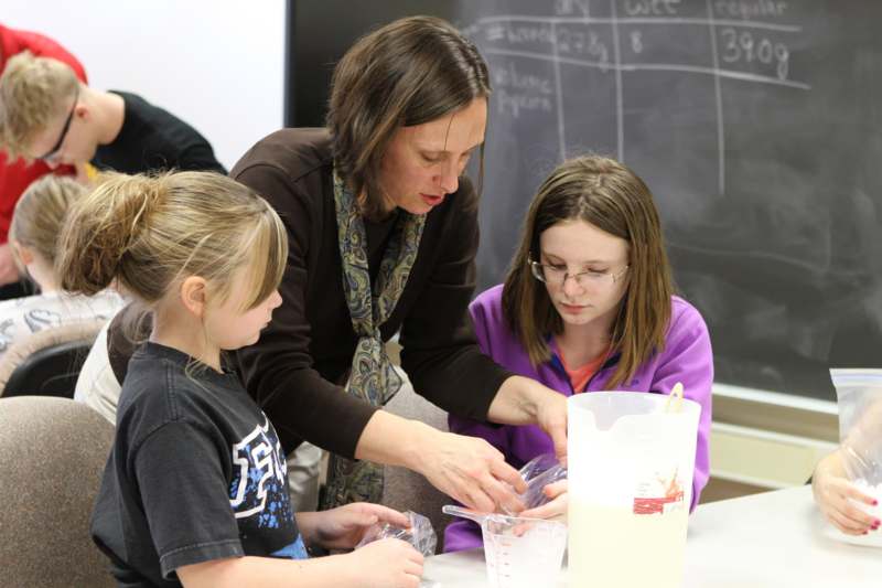 a woman and two girls working on a science experiment