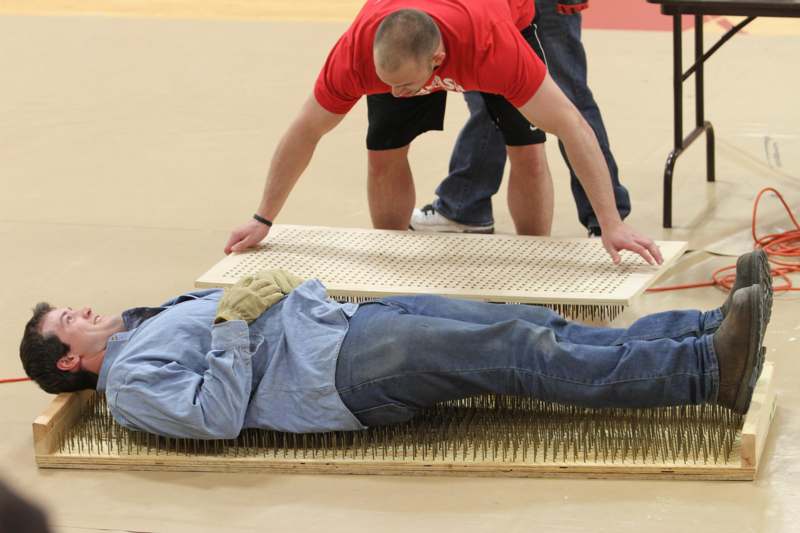 a man lying on a mat with nails