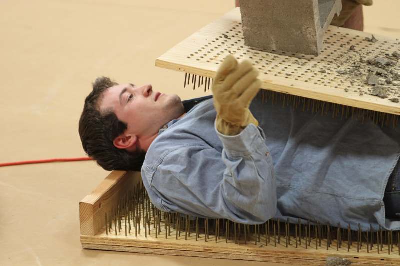 a man lying on his back in a wooden box with nails