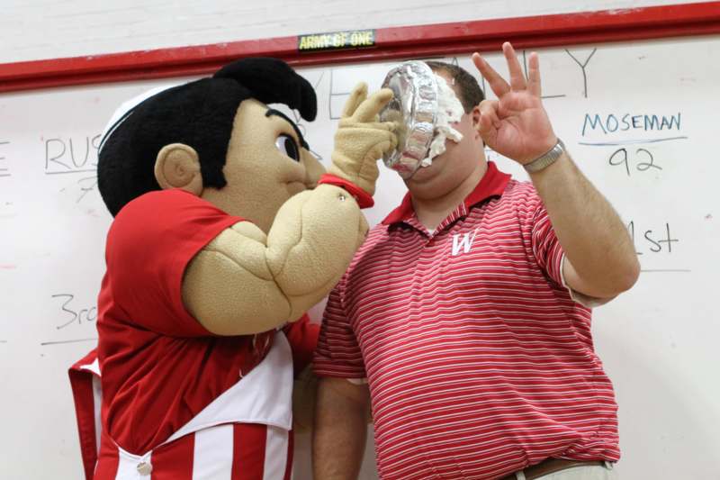 a person with a large mascot holding a silver bowl over his face