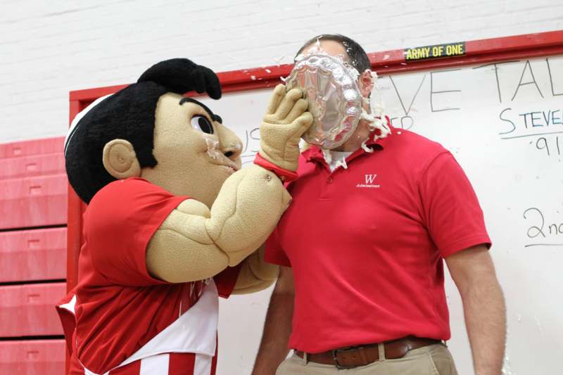 a person in a red shirt with a large mascot on his face